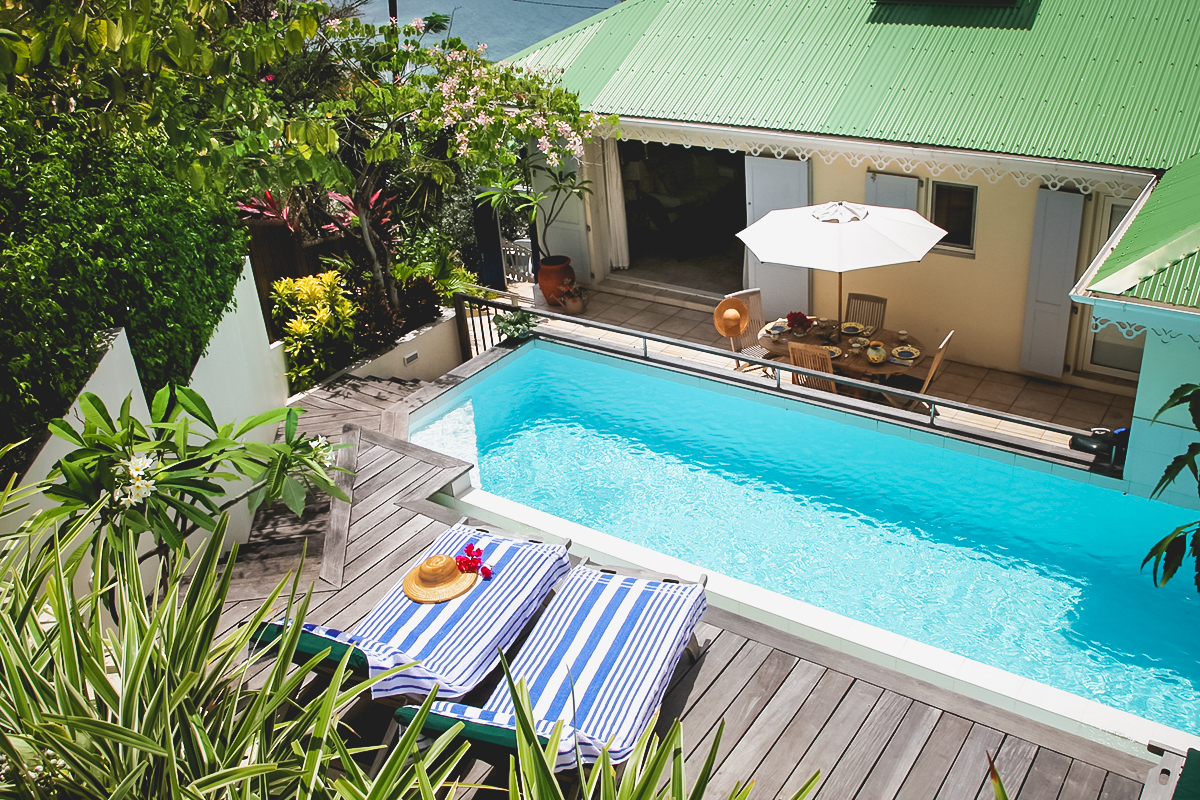 Sunlit pool terrace with striped loungers and tropical garden at private villa rentals St Barts.