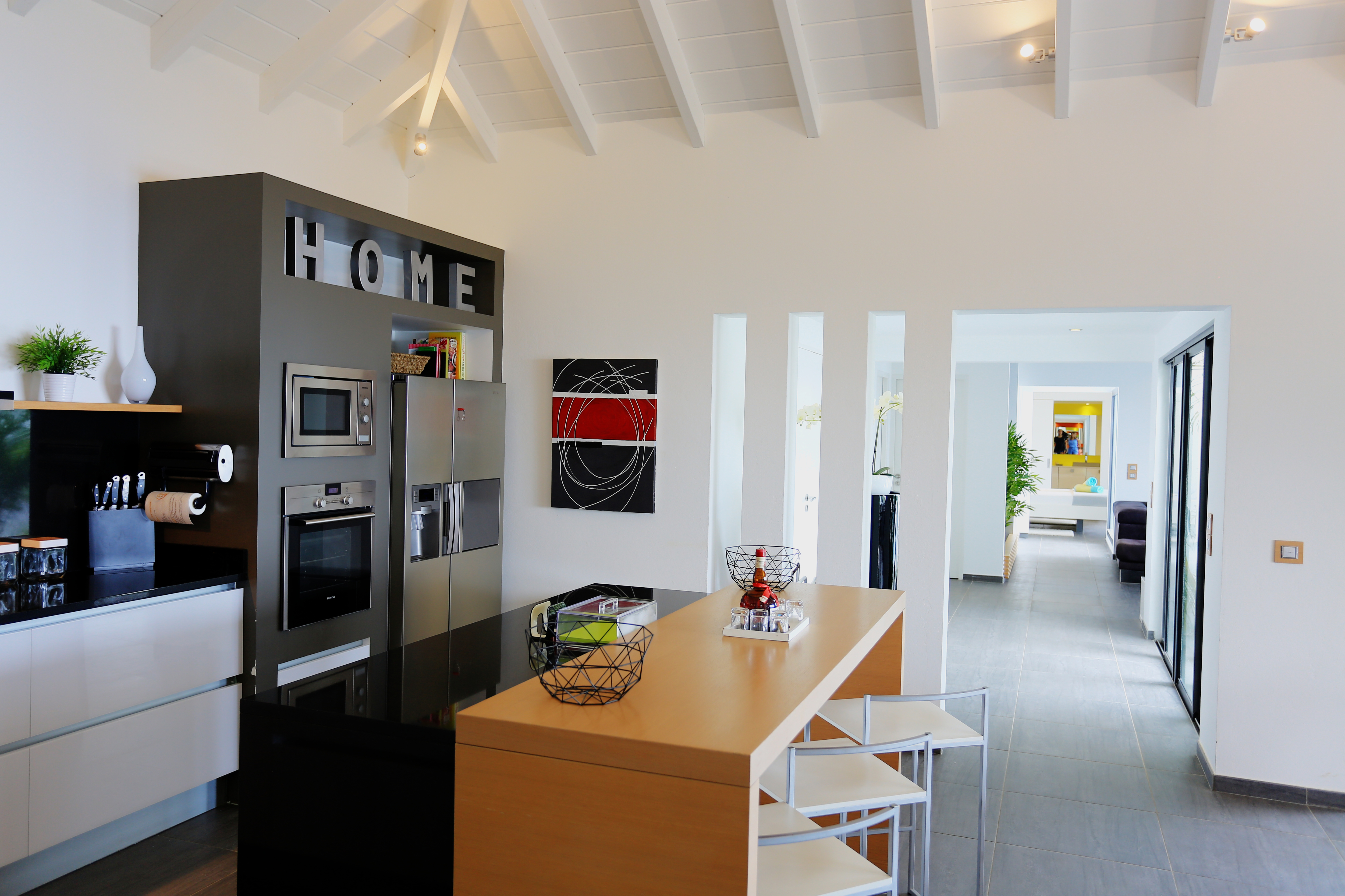 Modern kitchen with breakfast bar and open hallway leading to living area at a luxury villa in St Barts