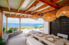 Open-air dining terrace with wooden table, woven pendant lights, and ocean views at a luxury villa in St Barts