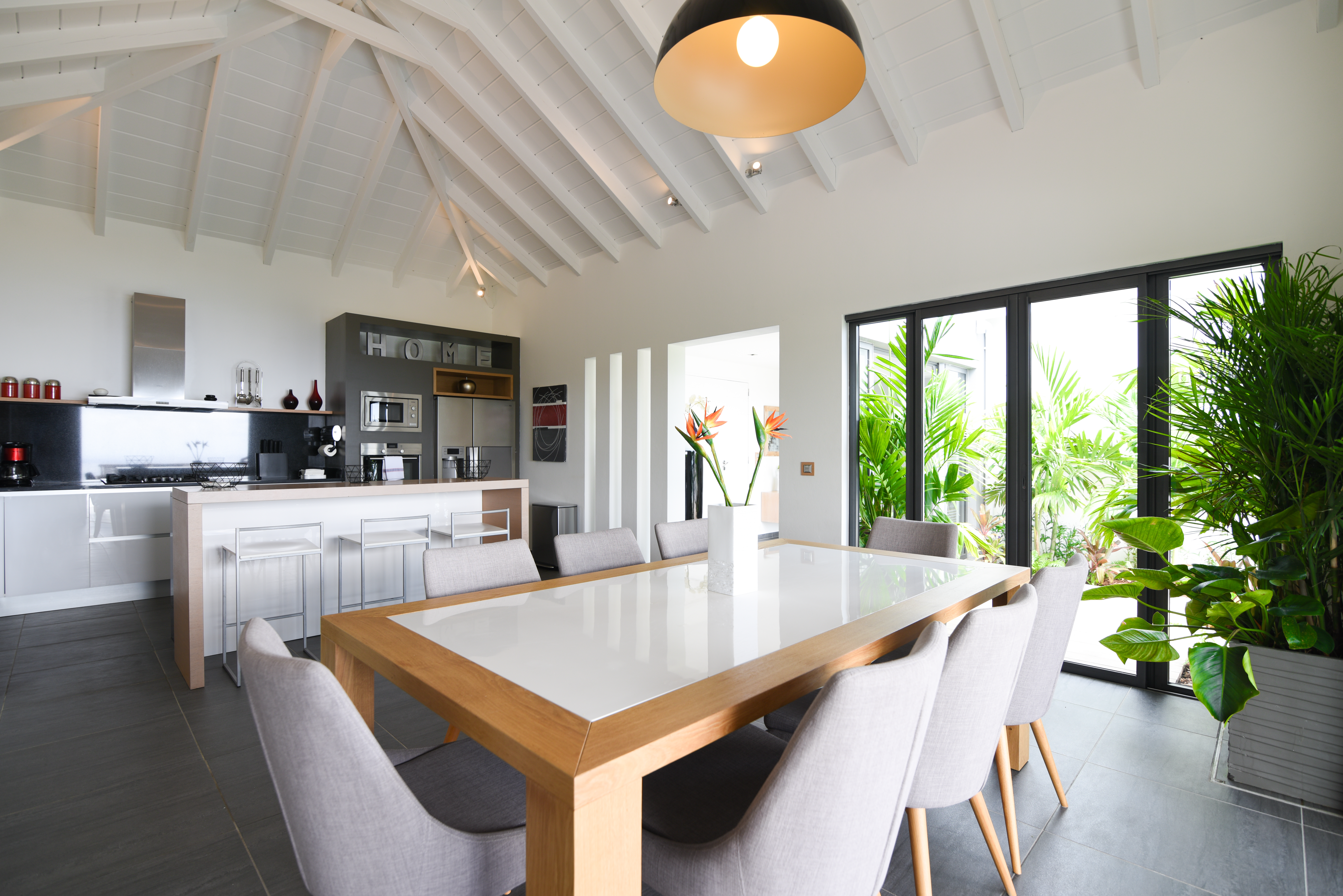 Contemporary dining area with modern kitchen and tropical garden view at a luxury villa in St Barts