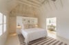 Bright bedroom with vaulted ceiling, neutral décor, and ensuite bathroom at a luxury villa rental in St Barts
