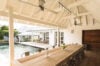 “Covered dining terrace with long wooden table overlooking private pool at a luxury villa in St Barts