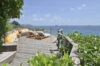 Clifftop wooden deck with sun loungers and colorful cushions overlooking the Caribbean Sea at luxury villa in St Barts.