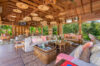 Open-air living room with wooden ceilings, rattan furniture, and tropical garden views at a luxury St Barts villa rental