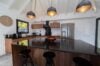 Modern kitchen with wood cabinetry, black countertops, and pendant lighting inside a luxury St Barts villa rental.