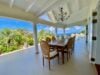 Elegant covered dining terrace with wooden table, chandelier, and ocean views at a luxury villa in St Barts