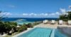 Infinity pool with panoramic ocean views and sun loungers surrounded by lush greenery at a St Barts villa rental”