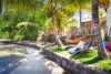 Beachfront garden with hammocks and lounge chairs shaded by palm trees at Villa Plumbago, st barts villa rental