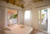 Cozy bedroom with soft natural light and balcony access overlooking the beach at a St Barts villa rental.