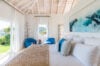 Bright coastal bedroom with blue accents and garden view, private villa rental in St Barts