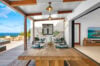 Covered dining terrace with wooden table and ocean view beside open living room at a luxury villa in St Barts