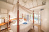 Elegant four-poster bed and pool view in bright Caribbean-style bedroom at luxury villa rental in St Barthélemy.