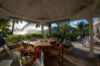 Covered outdoor dining pavilion surrounded by palm trees with sunset view at private villa rental in St Barthélemy.