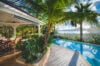 Tropical poolside terrace with dining pavilion and palm trees overlooking the sea at luxury villa rental in St Barths.