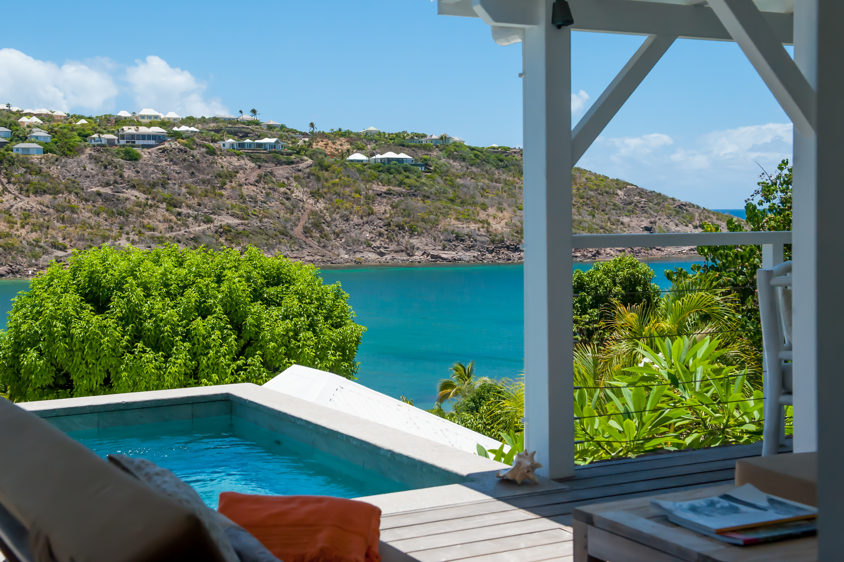 Private plunge pool overlooking turquoise bay at vacation rental St Barth surrounded by tropical greenery.