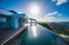 Infinity pool reflecting the morning sun at luxury villas St Barts overlooking Caribbean hills and sea.