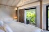 Serene bedroom in st barts villa with soft natural light and tropical garden view.