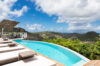 Curved infinity pool at luxury st barts villa with panoramic mountain and ocean views.
