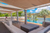Shaded outdoor lounge with infinity pool and lagoon views at a modern St Barths luxury villa rental.