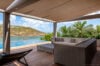 Covered terrace with modern lounge and infinity pool overlooking the lagoon at a St Barts villa rental