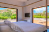 Contemporary bedroom opening to a sunlit terrace with garden and hillside views at a St Barths villa rental.