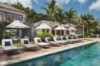 Sun loungers and umbrellas by long turquoise pool at luxury villa rental in St Barts surrounded by tropical gardens.