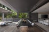 Elegant open-air dining area with a long black table and lounge space, blending seamlessly with a modern living room and tropical garden views