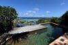 Hilltop pool with ocean view and sun loungers surrounded by greenery at Villa Plumbago, st barts villa rental