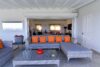 Outdoor lounge with grey rattan sofas and orange cushions connecting to indoor living space at a St Barts villa rental