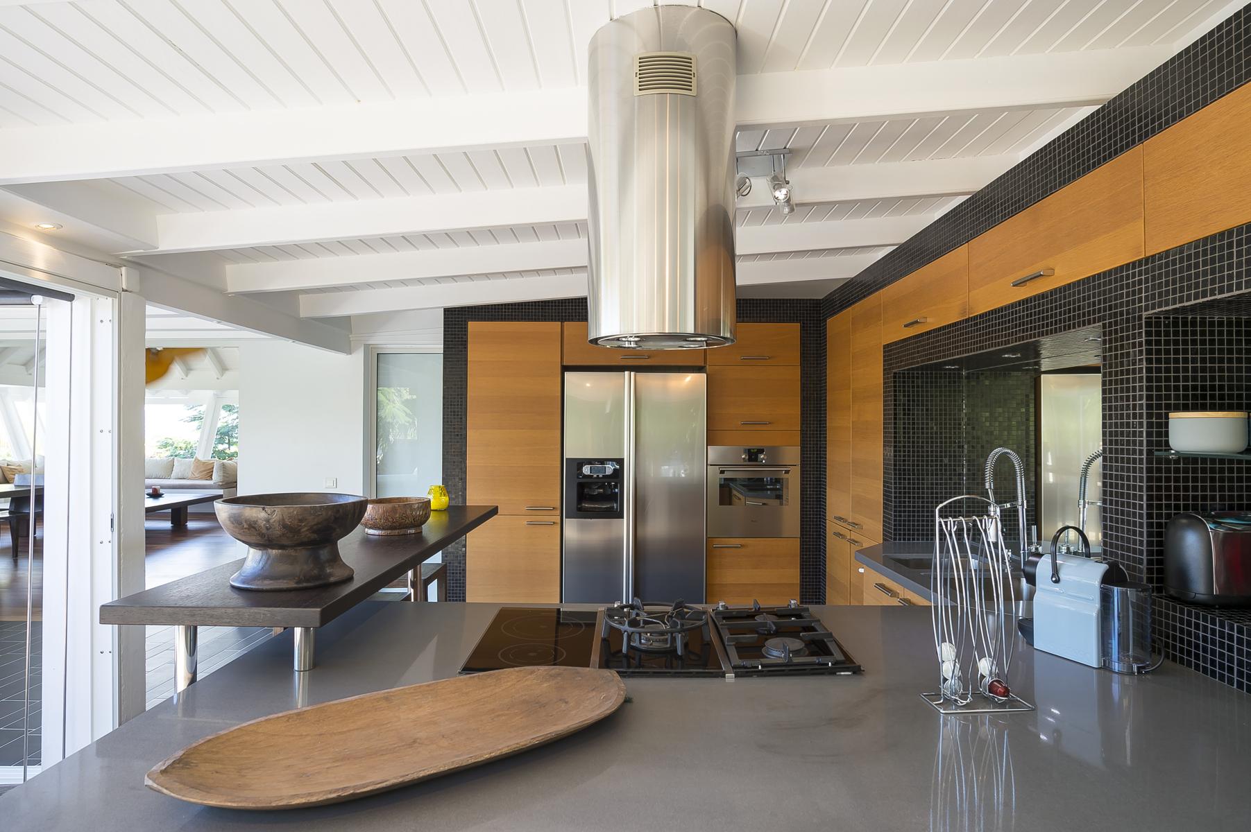 St Barts villa rentals with modern kitchen featuring stainless steel appliances, wooden cabinetry, and sleek island countertop.