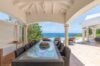 Covered outdoor dining area at st barts villa rentals with ocean view, vaulted ceiling, and elegant island design.