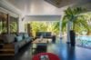 Open-air living area with modern sofas and poolside view surrounded by tropical palms at a St Barts villa rental