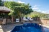 Luxury villas St Barts with blue-tiled pool, sun loungers, and shaded outdoor dining beneath tropical trees.