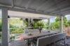 Covered terrace dining area in st barts villa overlooking turquoise bay and lush tropical hills.