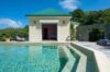 Sunlit swimming pool beside guest pavilion with green roof at Villa Plumbago, st barts villa rental