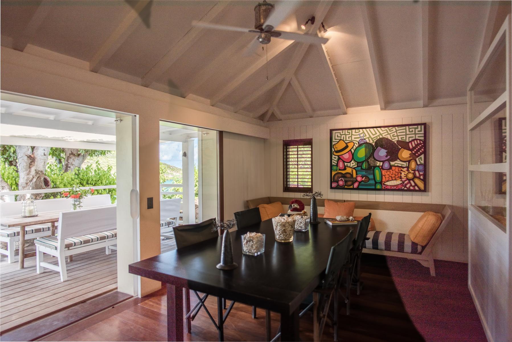 Indoor dining area with colorful artwork and terrace access at Villa Plumbago, st barts villa rental