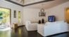 Minimalist living room with white sofas, modern décor, and garden access at a private villa rental in St Barts