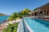 Infinity pool overlooking turquoise Caribbean waters surrounded by palms at Villa Plumbago, st barts villa rental