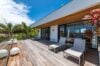 Spacious wooden terrace with sun loungers and tropical plants at contemporary villa rental in St Barths.