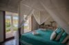 Serene bedroom with turquoise bedding and canopy, opening to ocean views at a St Barts villa rental