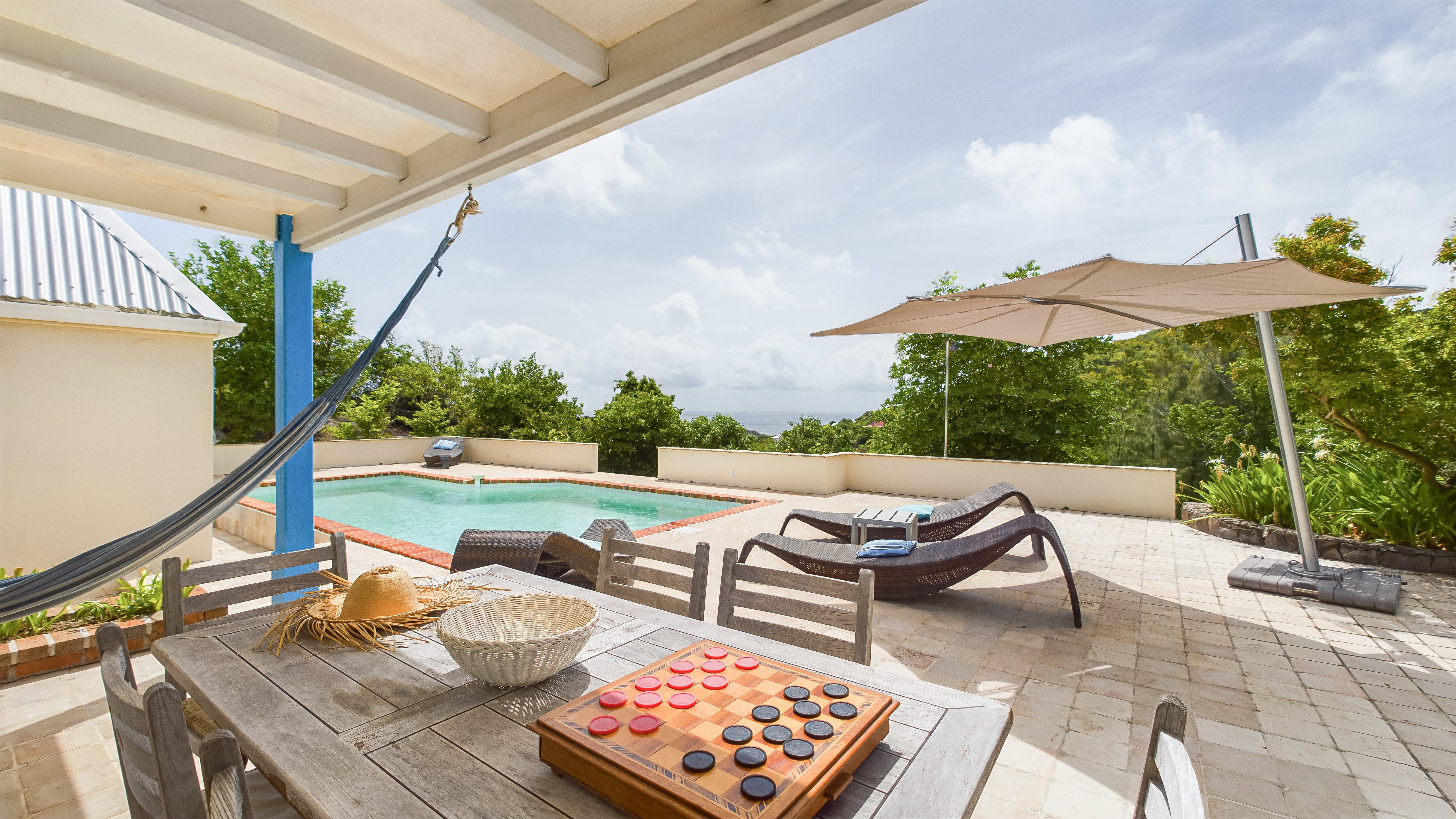 Covered terrace with hammock, dining table, and pool view at vacation rentals st barts