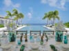Elegant alfresco dining table set by infinity pool with ocean view at luxury villa in St Barths.