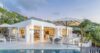Evening view of illuminated white villa with terrace and poolside lounge in St Barts.