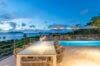 Elegant outdoor dining terrace with illuminated pool and ocean views at a St Barts luxury villa rental.