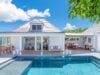 Sunlit pool and terrace in front of modern white villa rental in St Barthélemy with open living spaces.