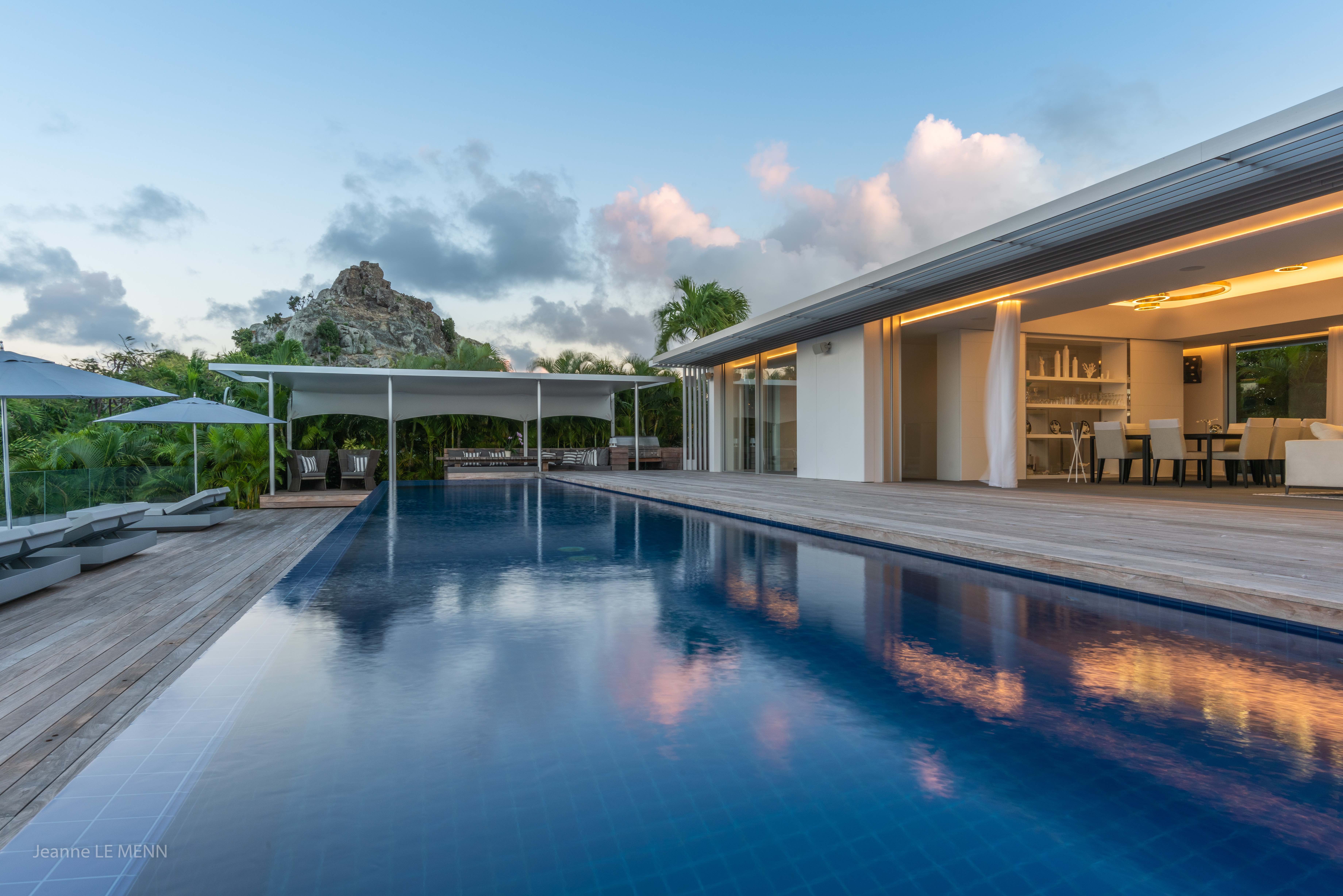 Evening view of sleek infinity pool and illuminated terrace at luxury villa rental in St Barths.