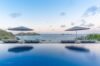 Infinity pool with sun loungers and umbrellas overlooking the Caribbean Sea at a luxury St Barts villa rental.