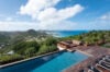 Infinity pool at luxury st barts villa with panoramic ocean view over lush island hills.