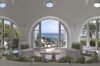 Bright living room of a St Barts villa with arched windows framing the ocean, white interiors, and soft green accents.