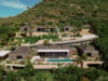 Aerial view of Villa Plumbago nestled in the green hills of Colombier, St Barts, featuring tiered pavilions, infinity pool, and tropical gardens.